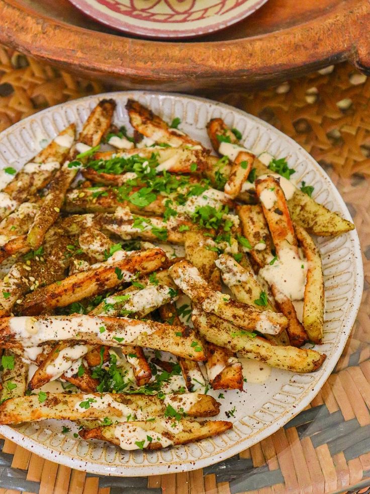 a white plate topped with french fries covered in parmesan cheese and garnished with herbs