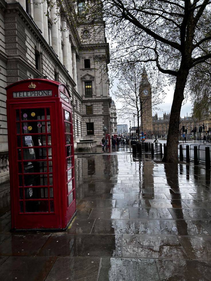 a red phone booth sitting on the side of a street