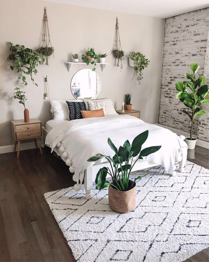 a bedroom with plants on the wall and a bed in the middle, next to a mirror