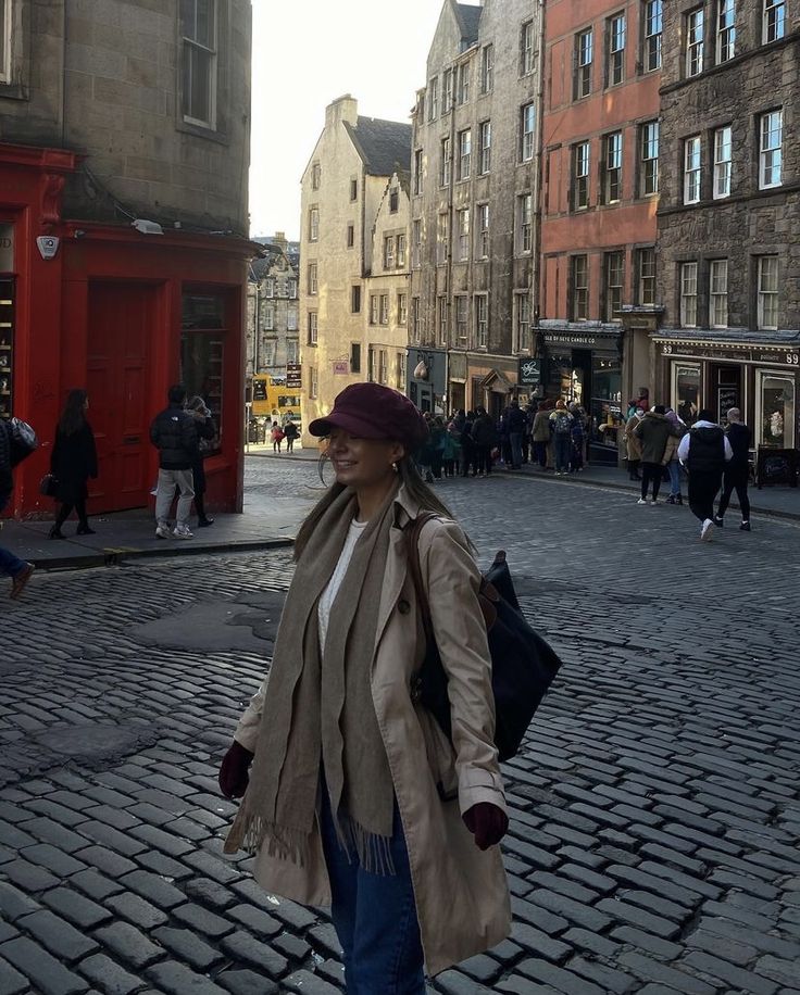 a woman is walking down the street in an old european city with many buildings and people