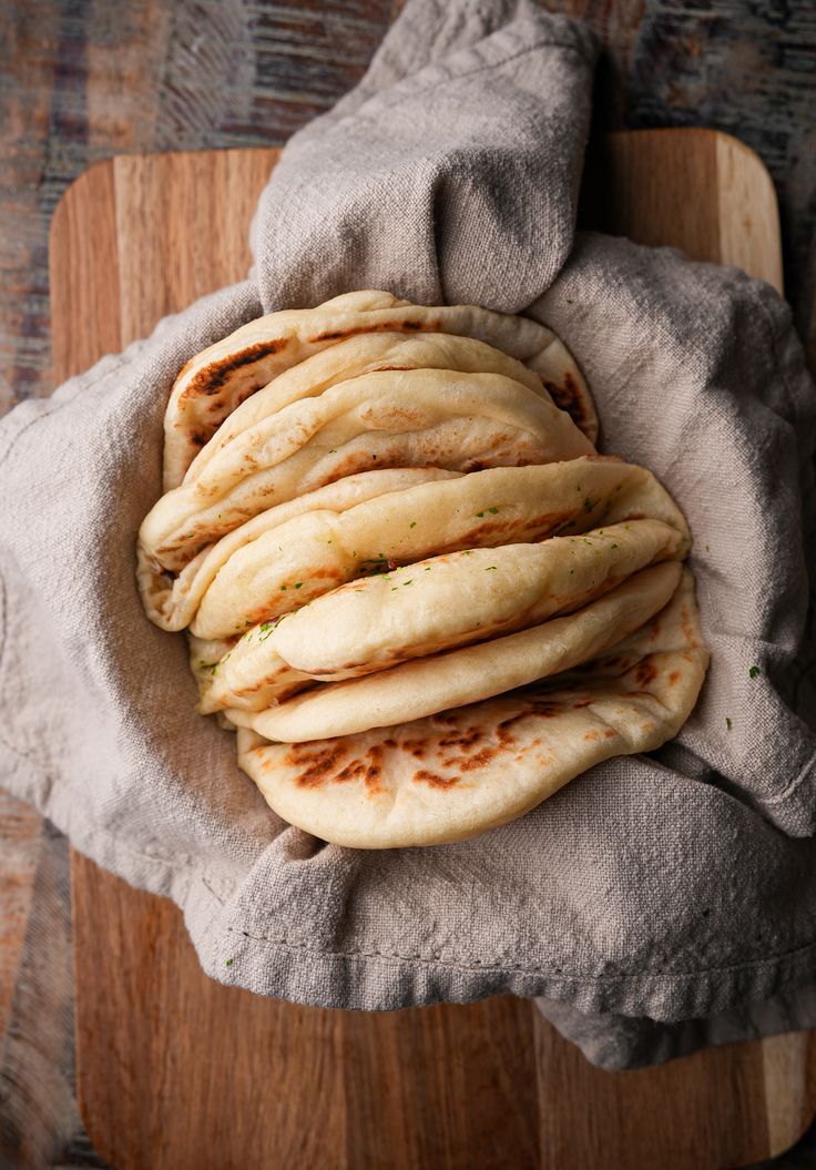 several pita breads stacked on top of each other in a wooden cutting board