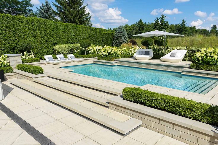 an outdoor swimming pool surrounded by shrubbery and lawn chairs