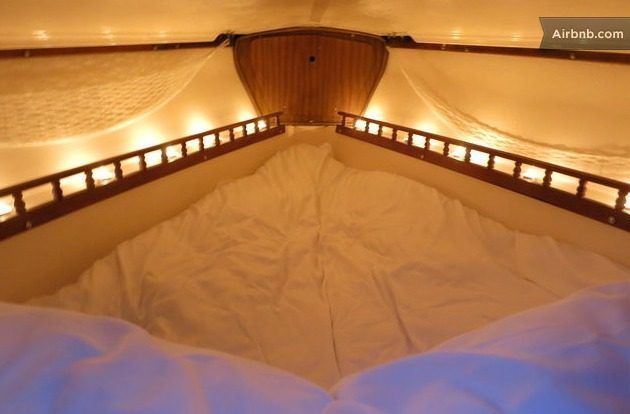 a bed with white sheets and pillows in a room that has lights on the walls