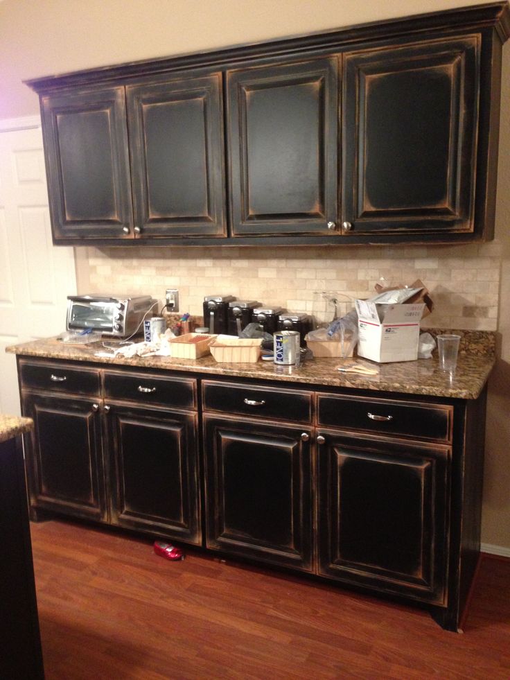 a kitchen with black cabinets and marble counter tops