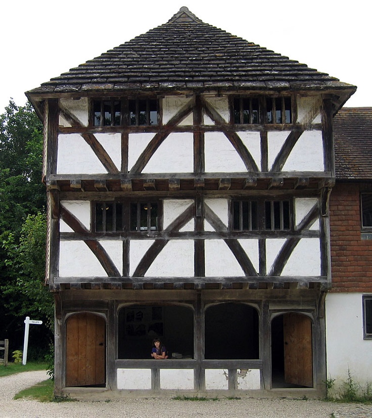 an old building with wooden and white trim on the front, next to some trees