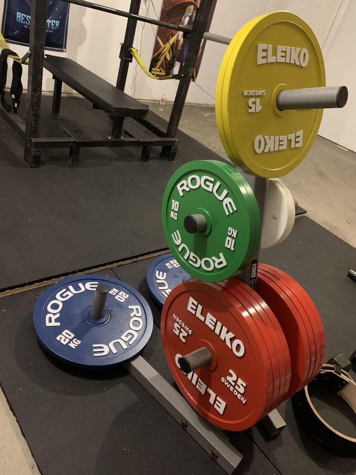 the weight plates are stacked on top of each other in front of a barbell rack