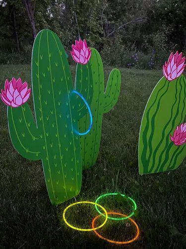 two large cactus sculptures with neon rings in the grass