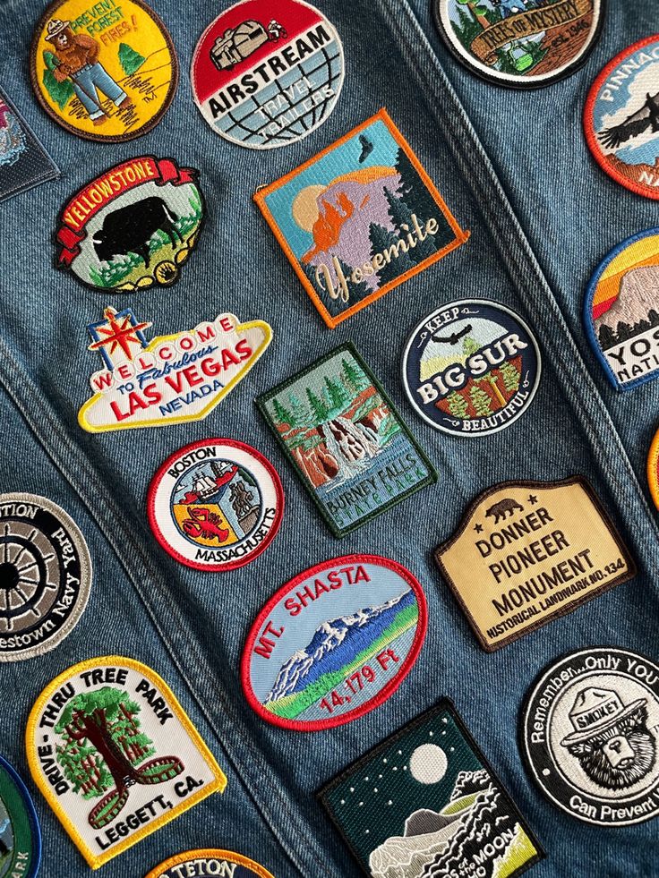 many different badges are on the back of a denim jacket that is covered in patches