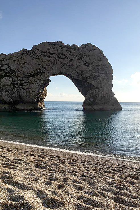 an arch shaped rock formation on the beach