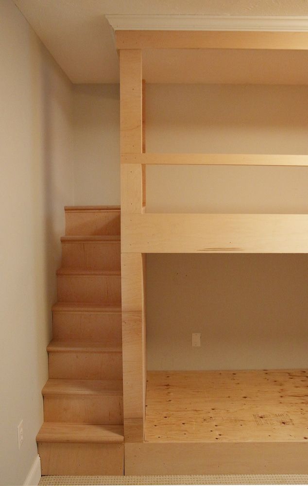 there is a bunk bed in the corner of this room with stairs leading up to it