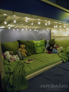 there is a bed with green sheets and stuffed animals on the bottom bunk, under lights