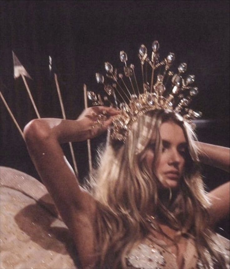 a woman wearing a gold crown and holding up her hair