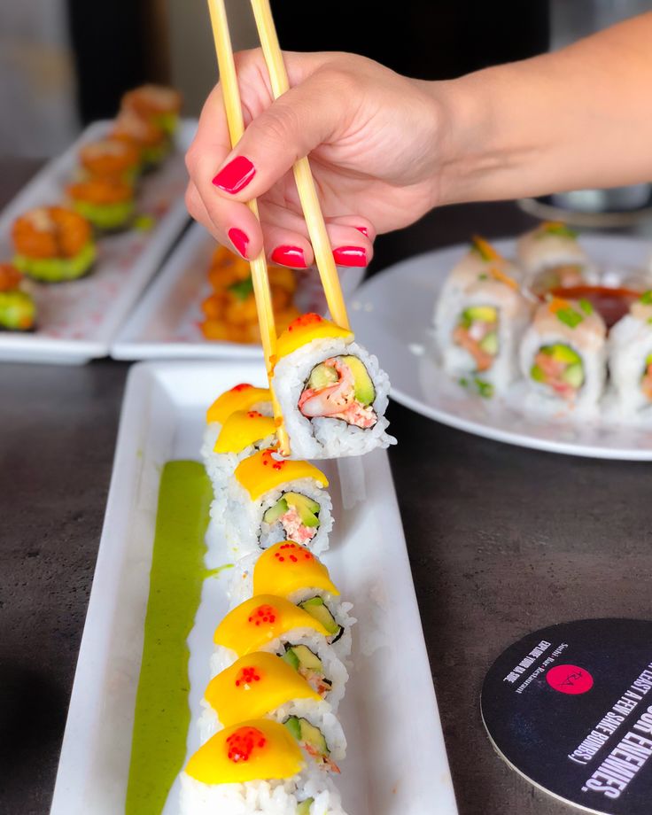 a woman is eating sushi with chopsticks