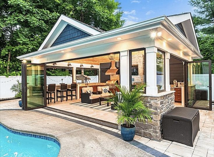 an outdoor living area with a pool and patio furniture in the foreground, surrounded by trees