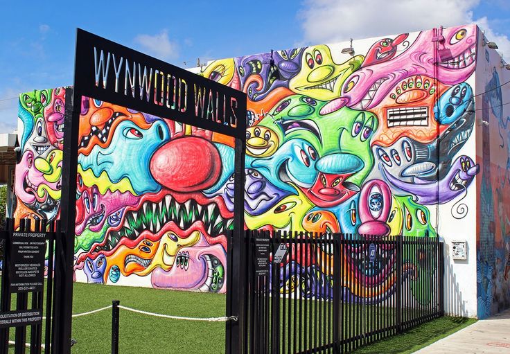 a large colorful mural painted on the side of a building next to a black fence