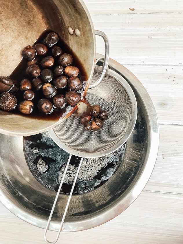 a metal bowl filled with nuts on top of a wooden table