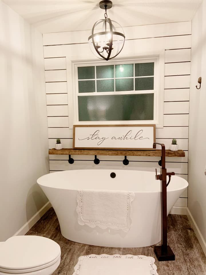 a white bath tub sitting next to a toilet in a bathroom under a light fixture