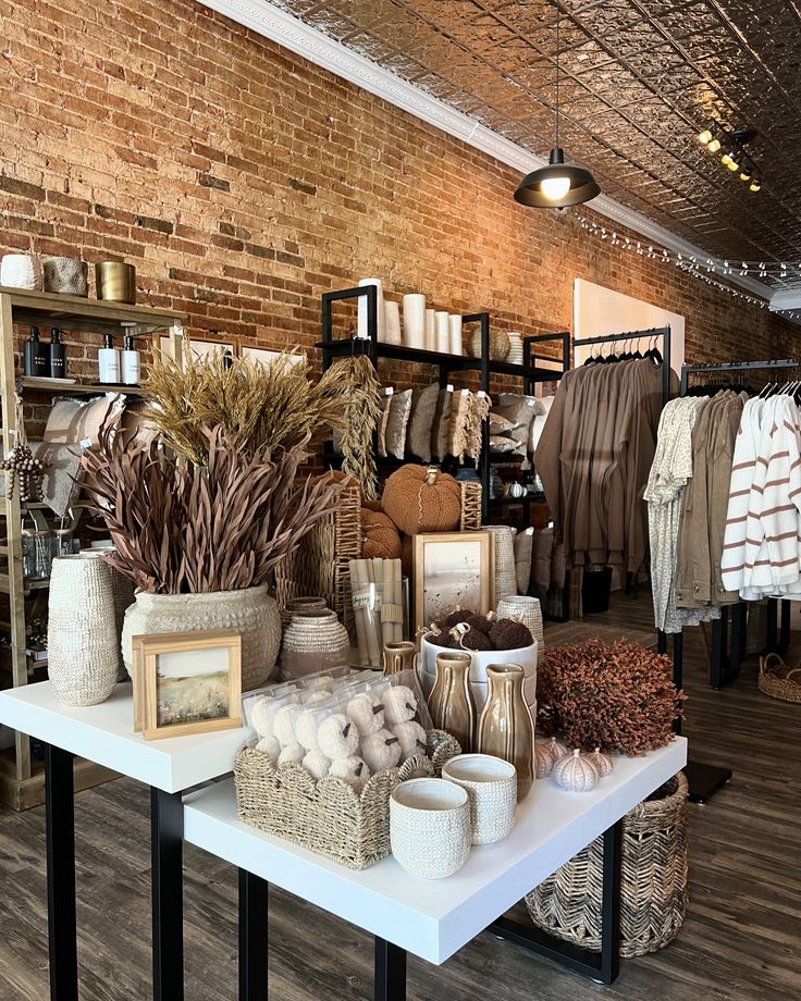 a room filled with lots of different types of clothing and accessories on tables in front of a brick wall