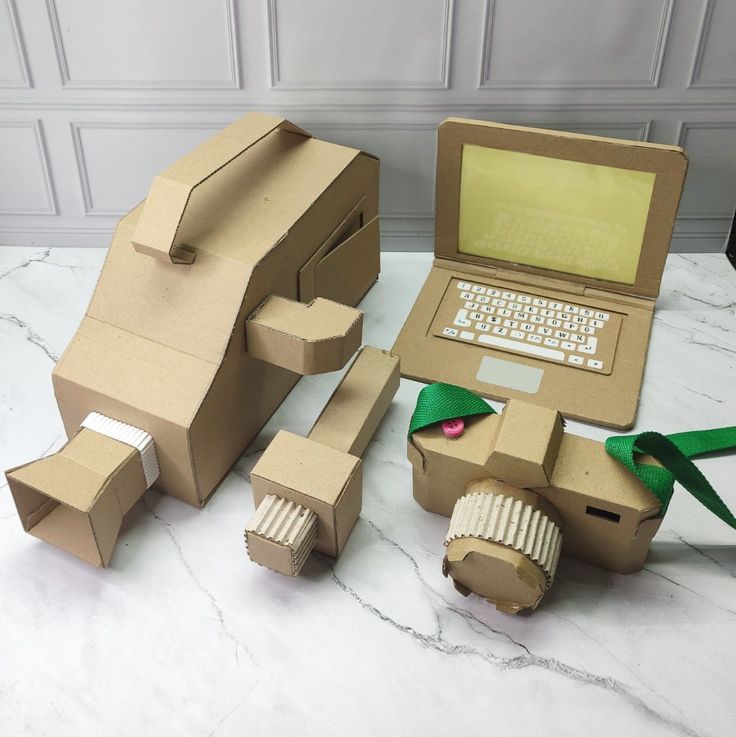 an open laptop computer sitting on top of a table next to cardboard boxes and ribbon