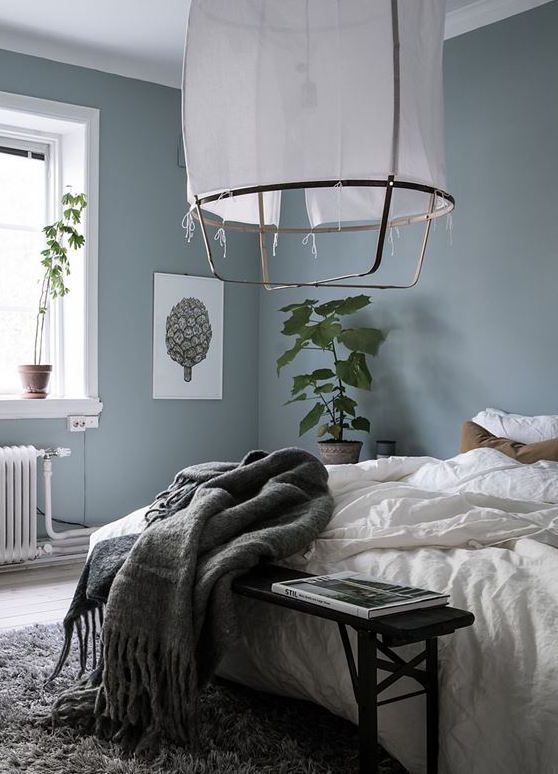 a bed with white sheets and blankets on it next to a large potted plant