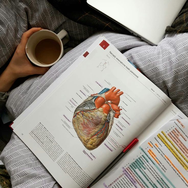 an open book on top of a bed next to a cup of coffee and a laptop