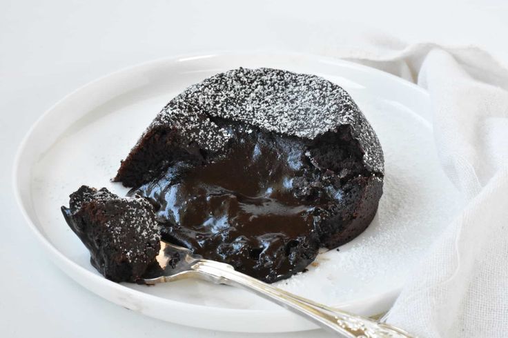 a piece of chocolate cake on a white plate with a fork and napkin next to it