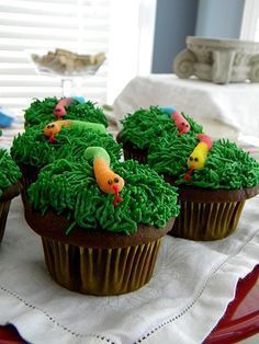 cupcakes with green frosting and decorations on a red plate in front of a window