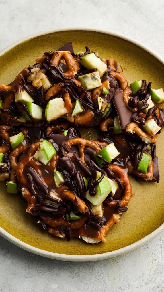 a plate topped with chocolate covered pretzels and apple slices on top of it