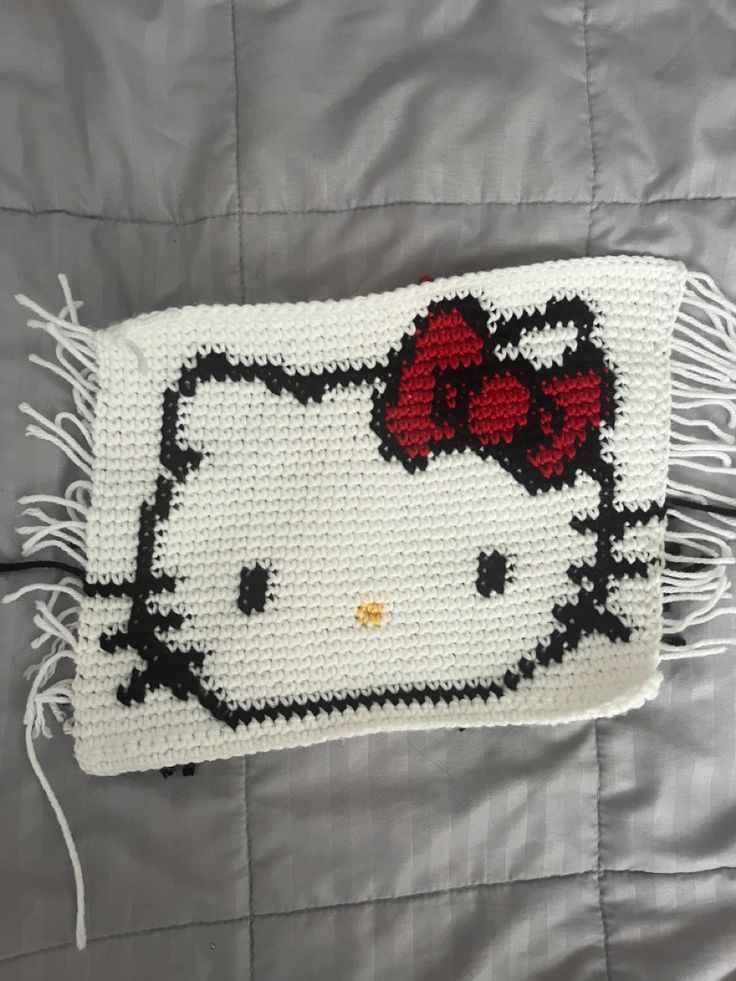 a crocheted hello kitty pillow with a red bow on it