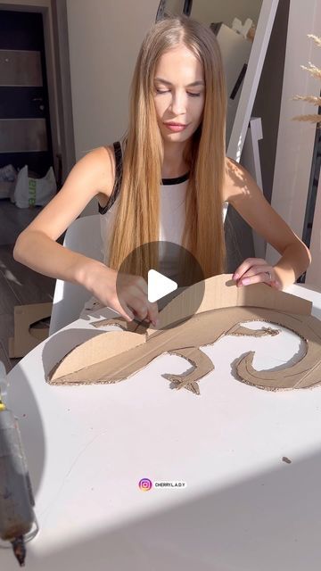 a woman is making an animal out of cardboard and glues it onto the table