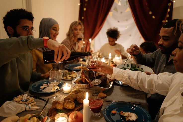 a group of people sitting around a table with food and candles in front of them