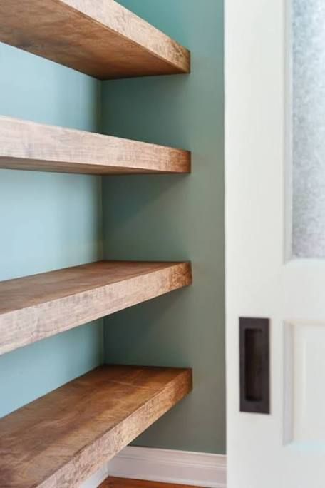 some shelves in a room with blue walls and wood flooring on the bottom shelf