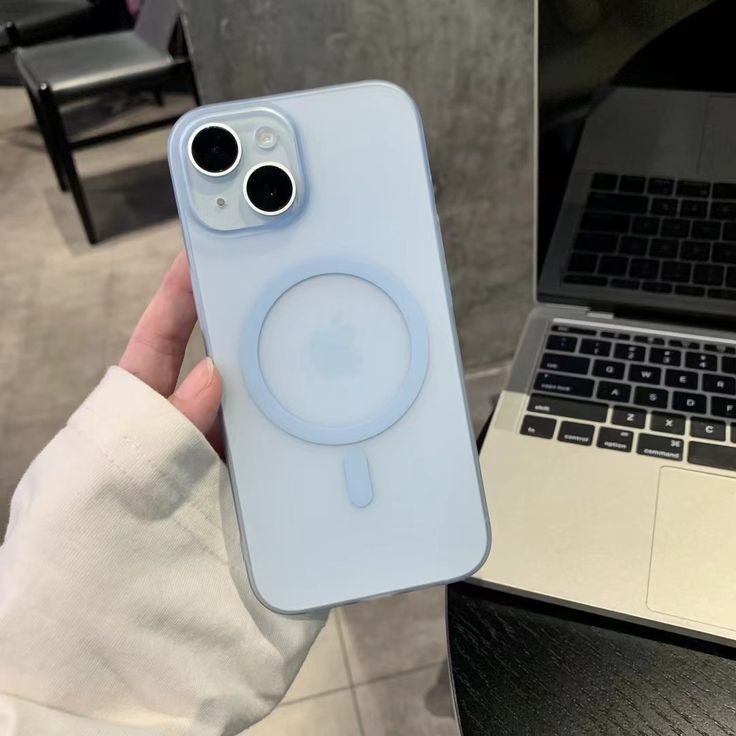 a person holding an iphone case in front of a laptop