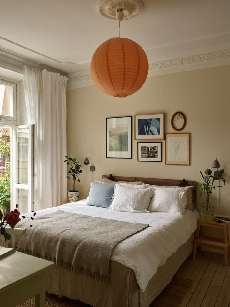 a bed sitting in a bedroom next to a window covered in white sheets and pillows