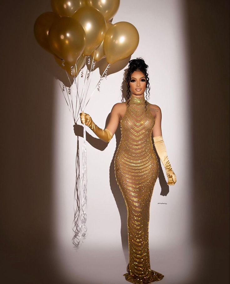 a woman in a gold dress holding some balloons