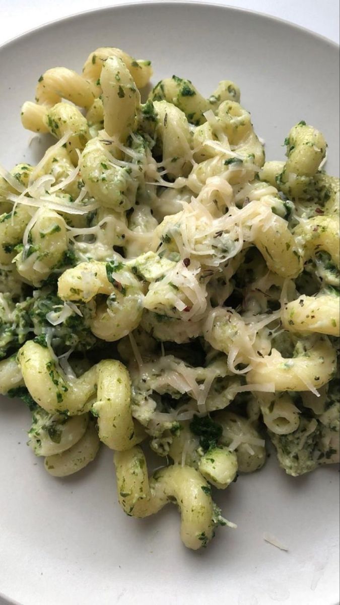 a white plate topped with pasta and broccoli covered in parmesan cheese