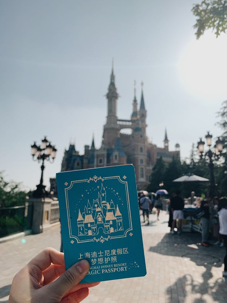 a person holding up a card in front of a castle with people walking around it