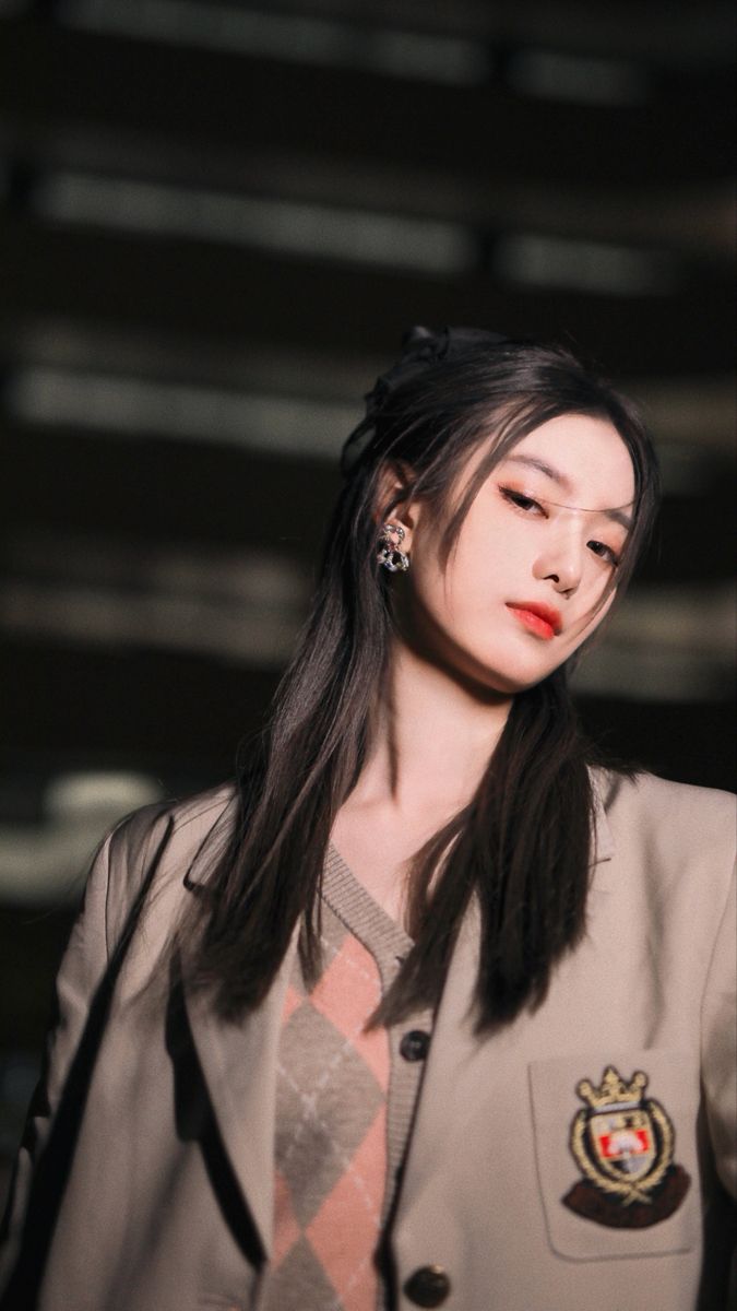 a woman with long black hair wearing a blazer and red lipstick on the runway