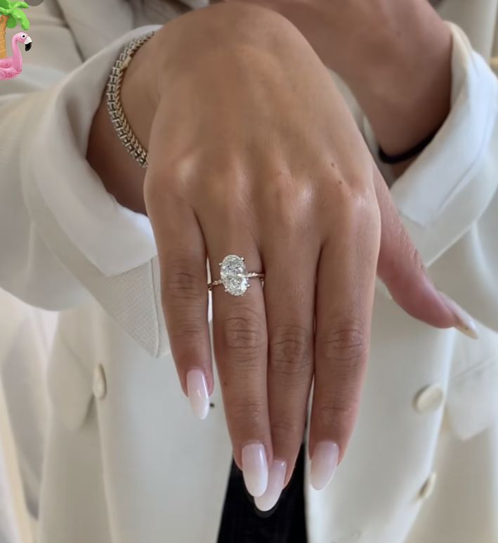 a close up of a person's hand with a diamond ring on their finger