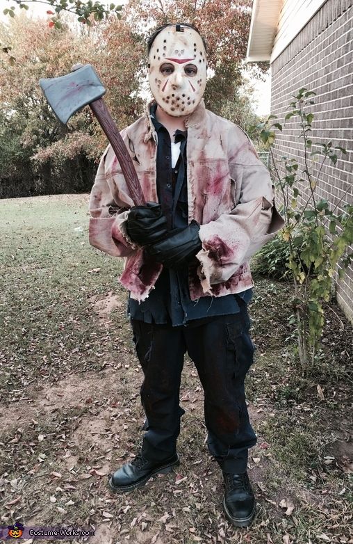 a man in a costume holding an axue and wearing a mask with blood on it