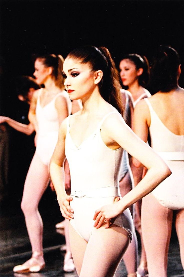 several ballet dancers in white leotards and one is standing with her hands on her hips