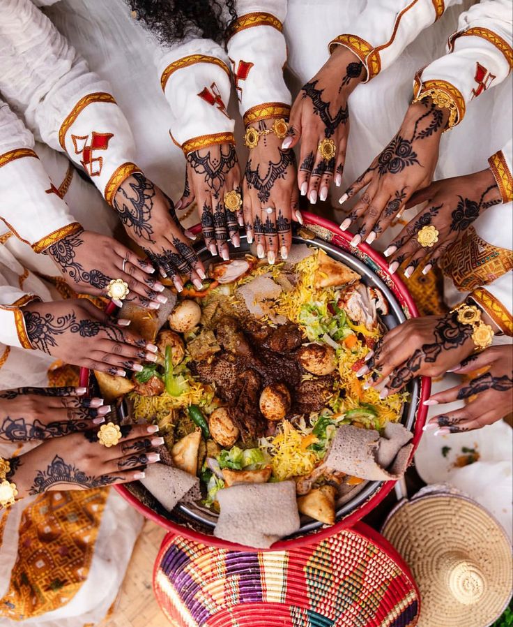 a group of people with their hands in the middle of a large bowl filled with food