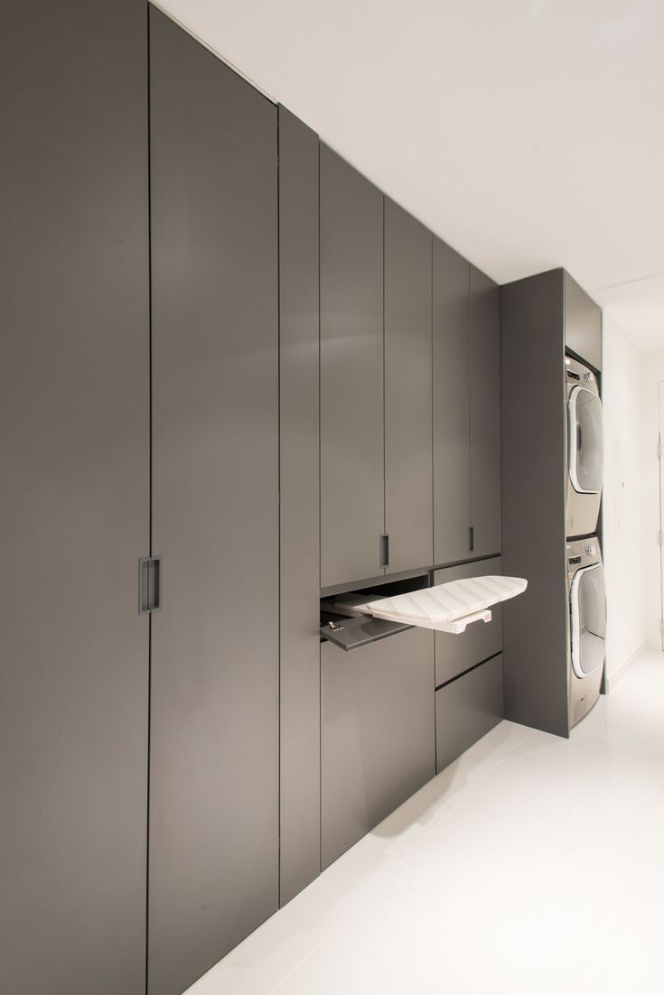 an empty kitchen with gray cabinets and white counter tops in front of a washer and dryer