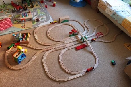 a child's toy train set laying on the floor next to a toddler bed