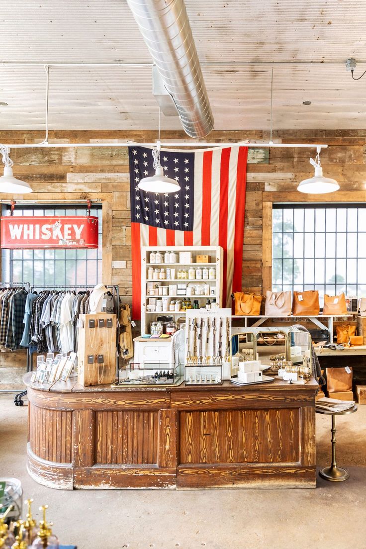 an american flag hangs in the window of a clothing store with clothes and other items on display