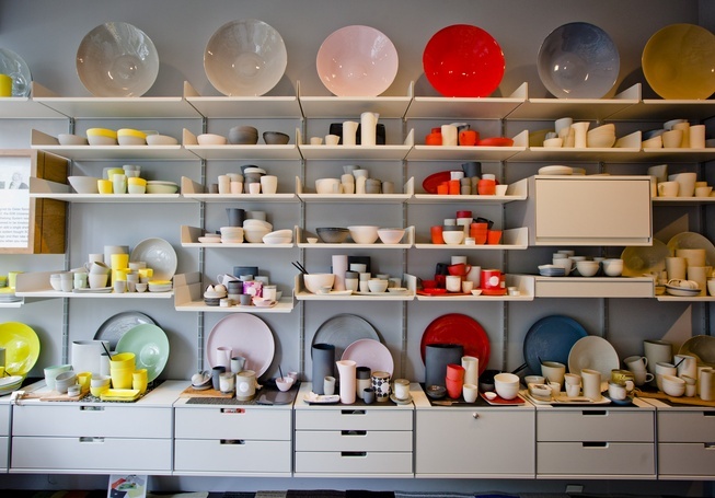 many plates and bowls are on shelves in a room that is filled with white cabinets