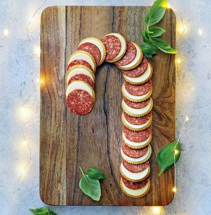 a wooden cutting board topped with slices of salami and sliced sausage on top of it