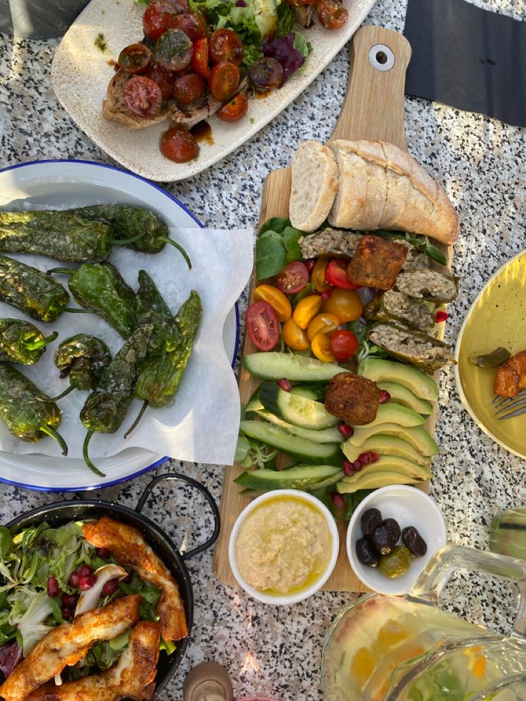 several plates of food on a table with bread, salads and other foods in bowls