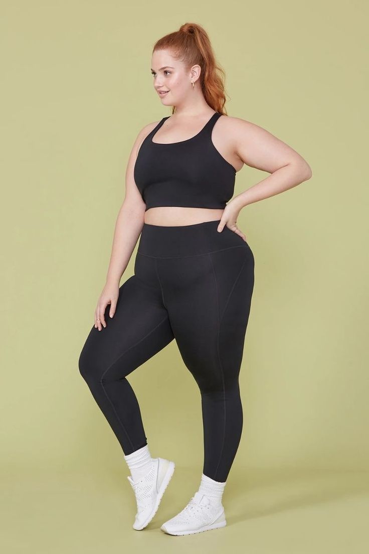 a woman in black sports bra top and leggings, posing for the camera