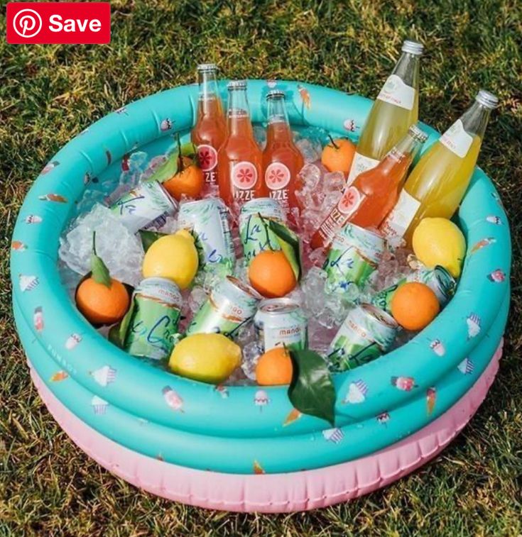 an inflatable pool filled with drinks and lemons on top of green grass